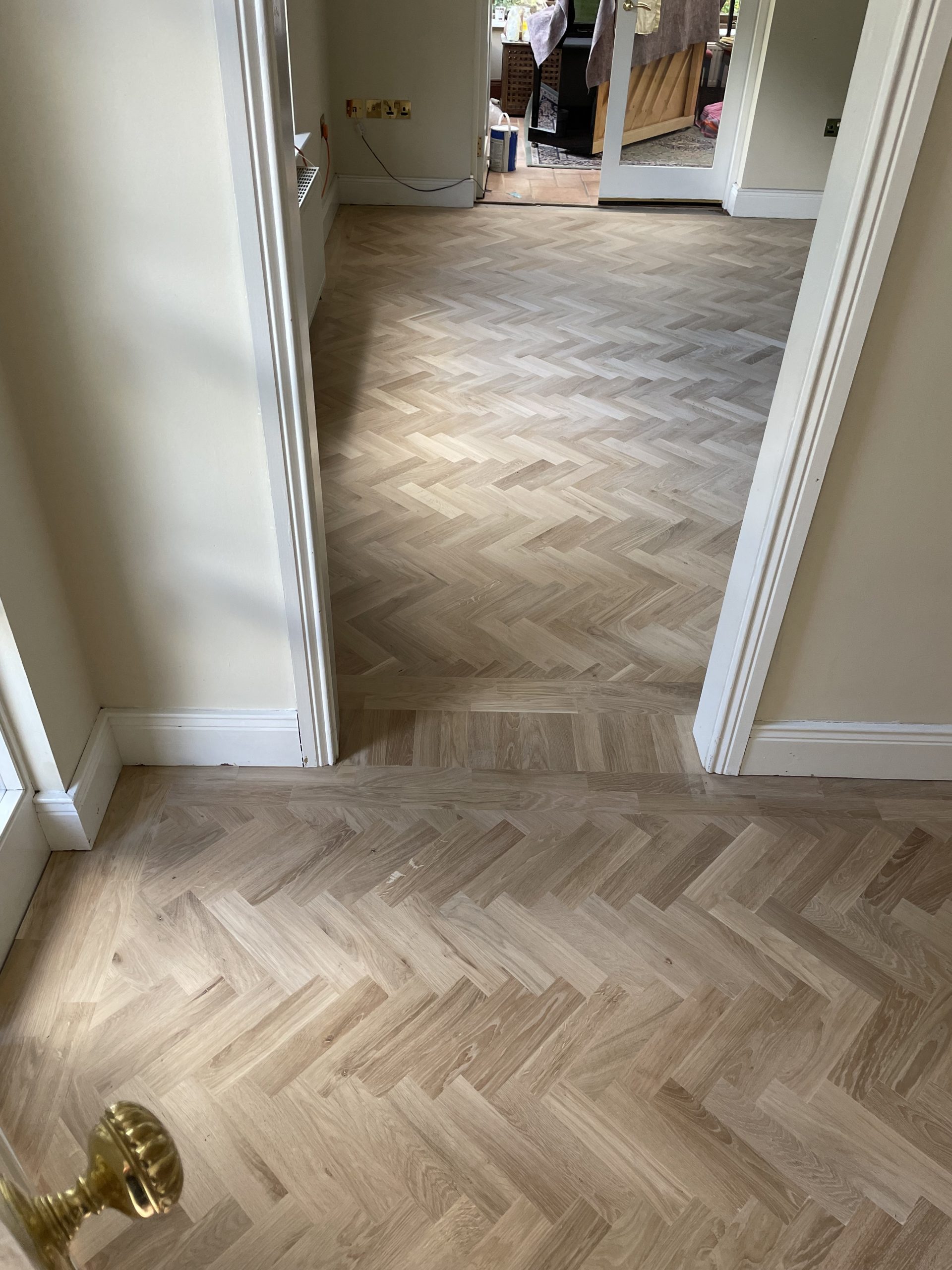 Oak herringbone flooring with a soldier course running through the doorway between adjoining rooms