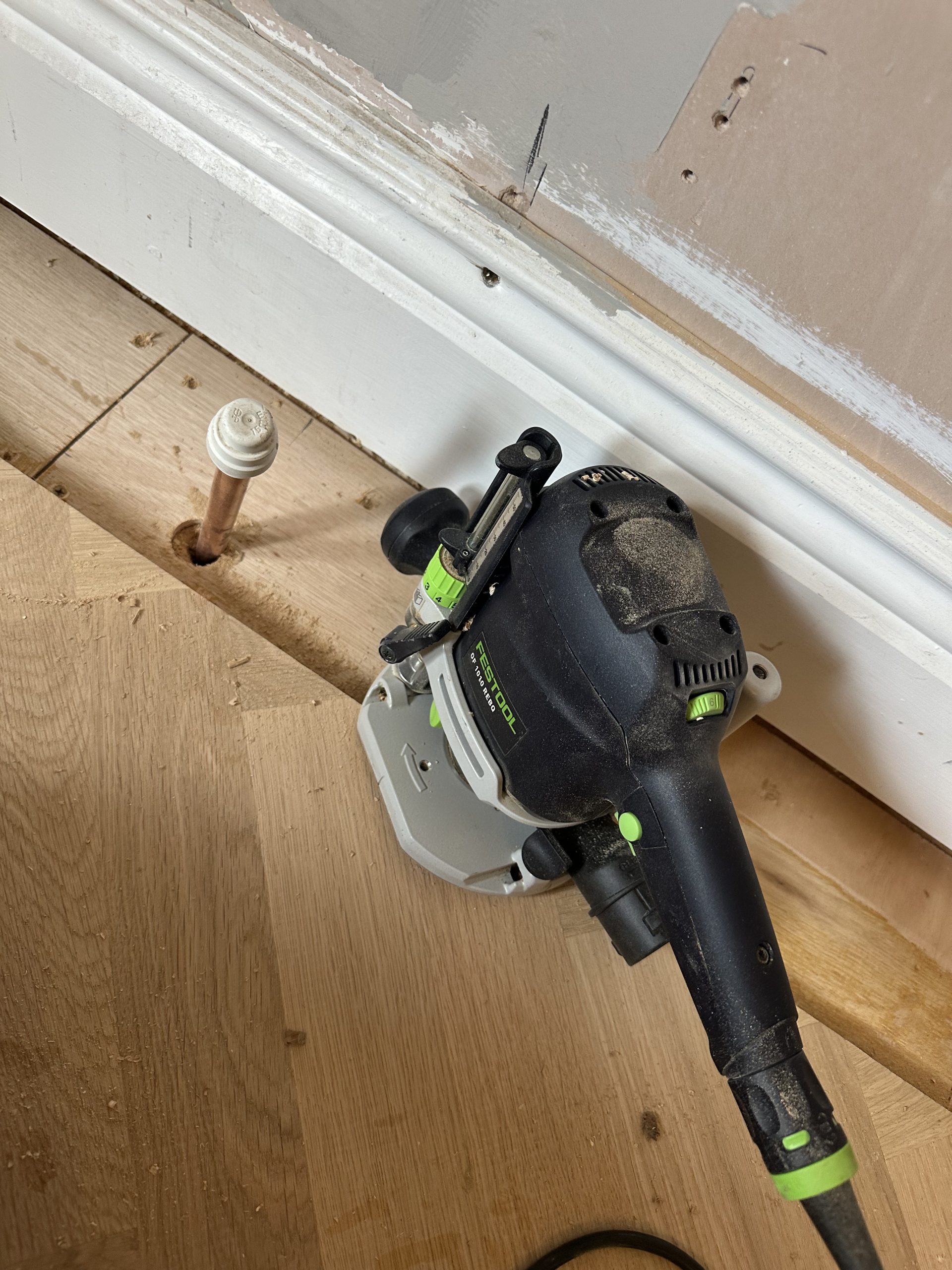 Festool router cutting a groove into the edge of a herringbone field for the border tongue