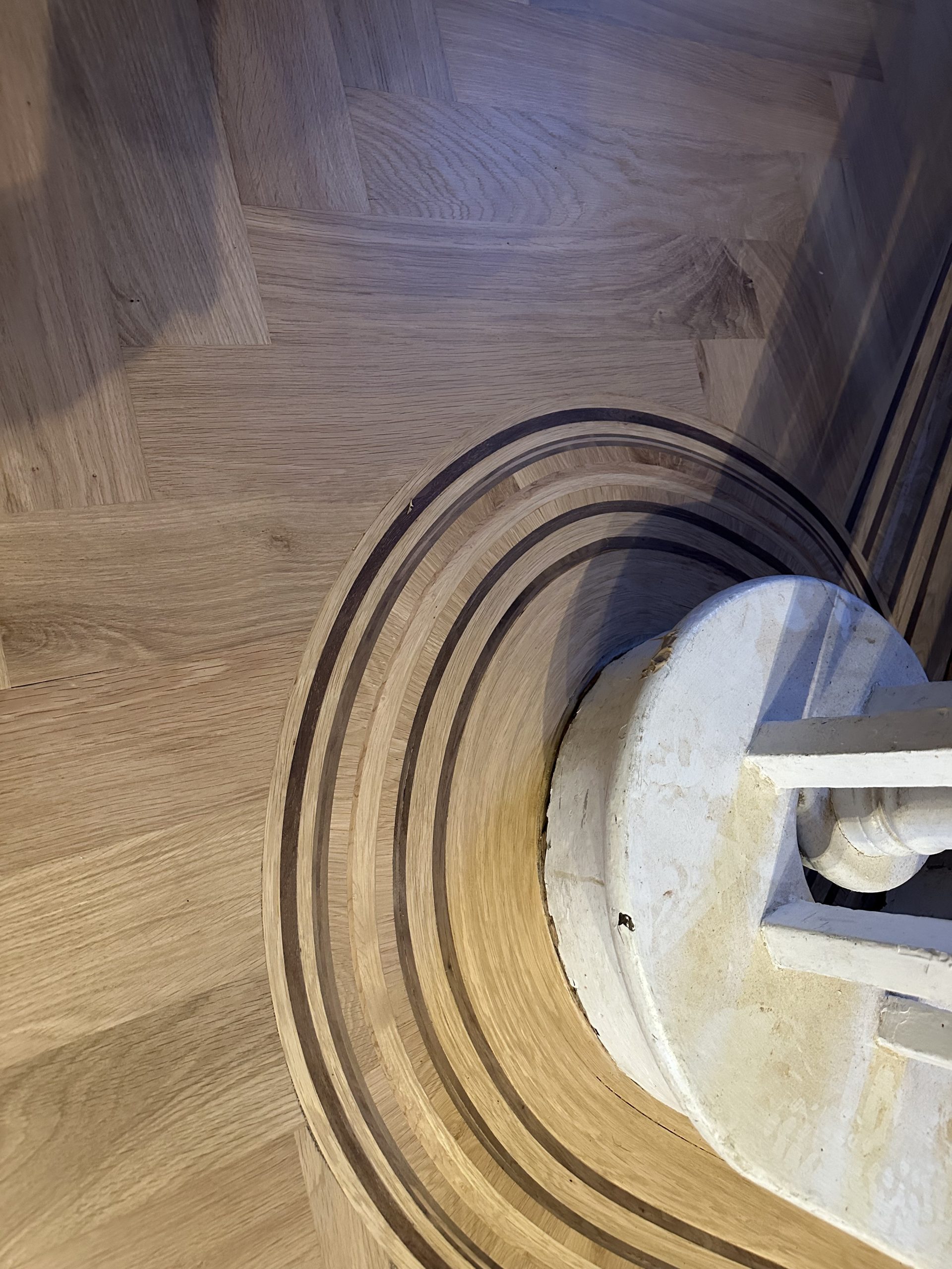 Curved Handmade Wood Floor Border Handmade multi-species wood floor border curved around a stair newel post