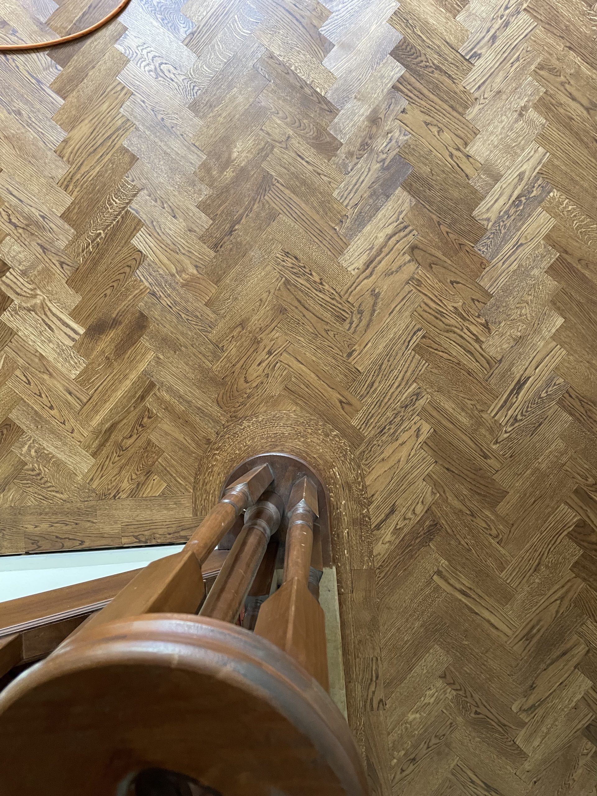 Overhead view of bespoke curved oak border around a staircase with herringbone flooring