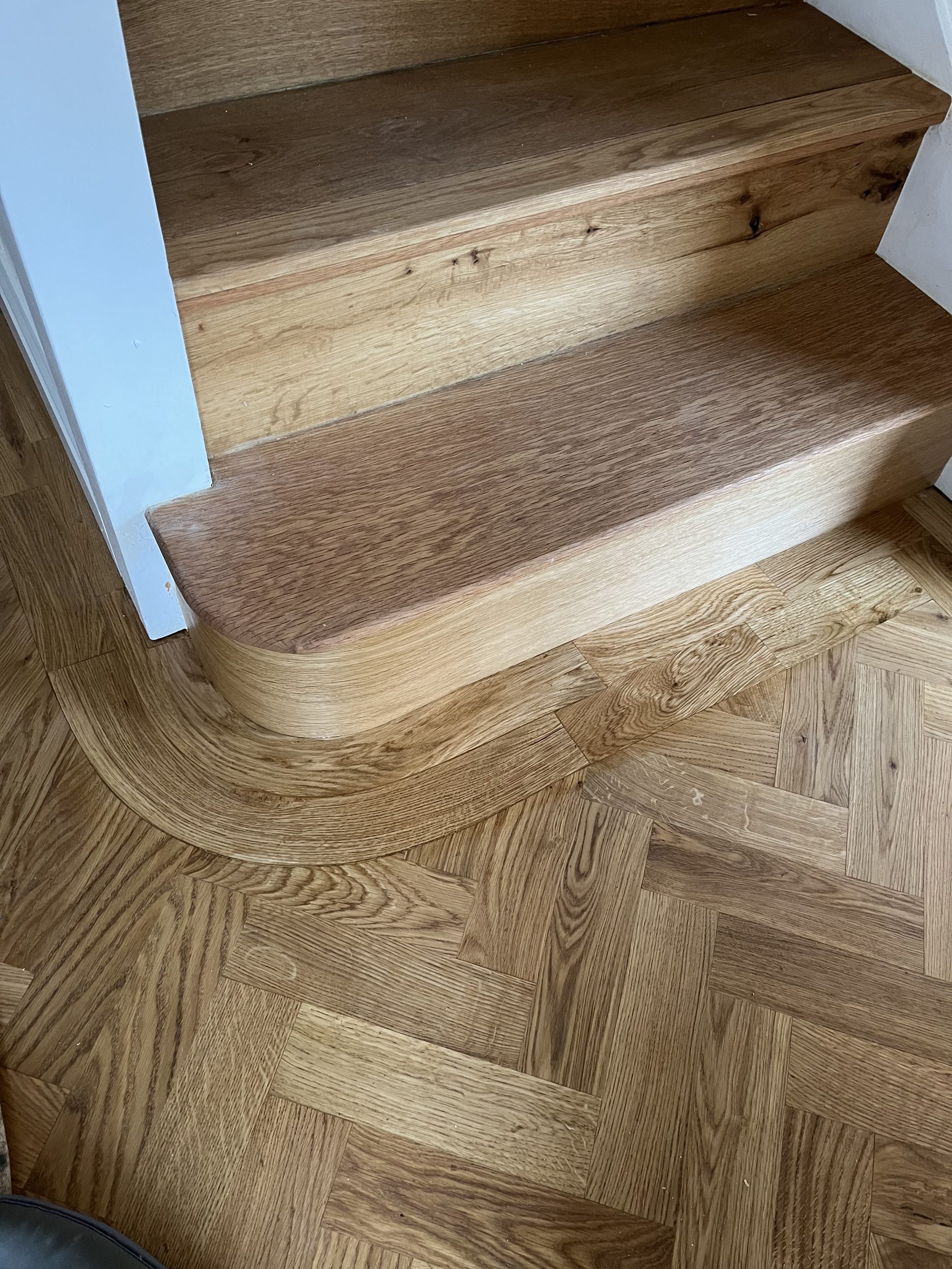 Curved Border Around Staircase Oak herringbone floor with a curved border following the bottom of a staircase