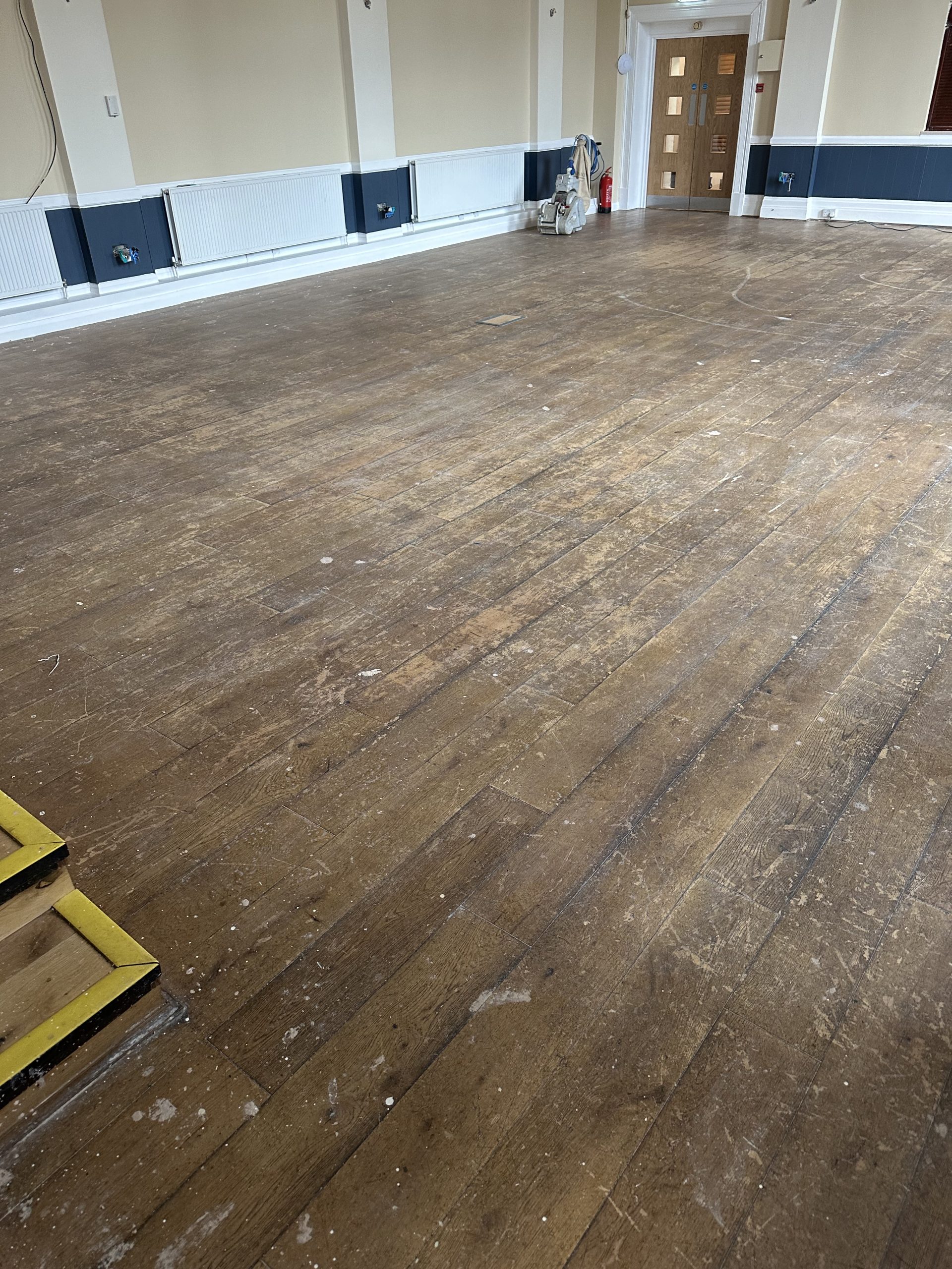 Heavily worn oak flooring in a Masonic hall before commercial floor restoration