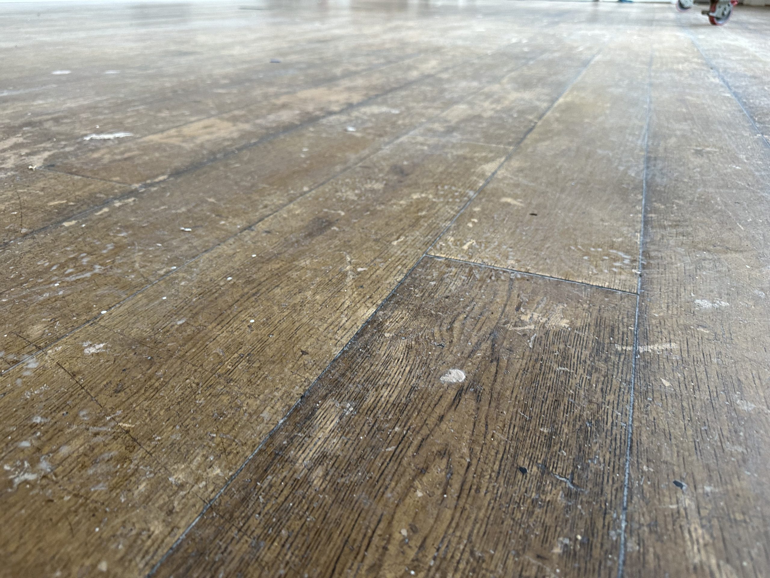 Close-up of scratches and worn finish on oak flooring before sanding and restoration