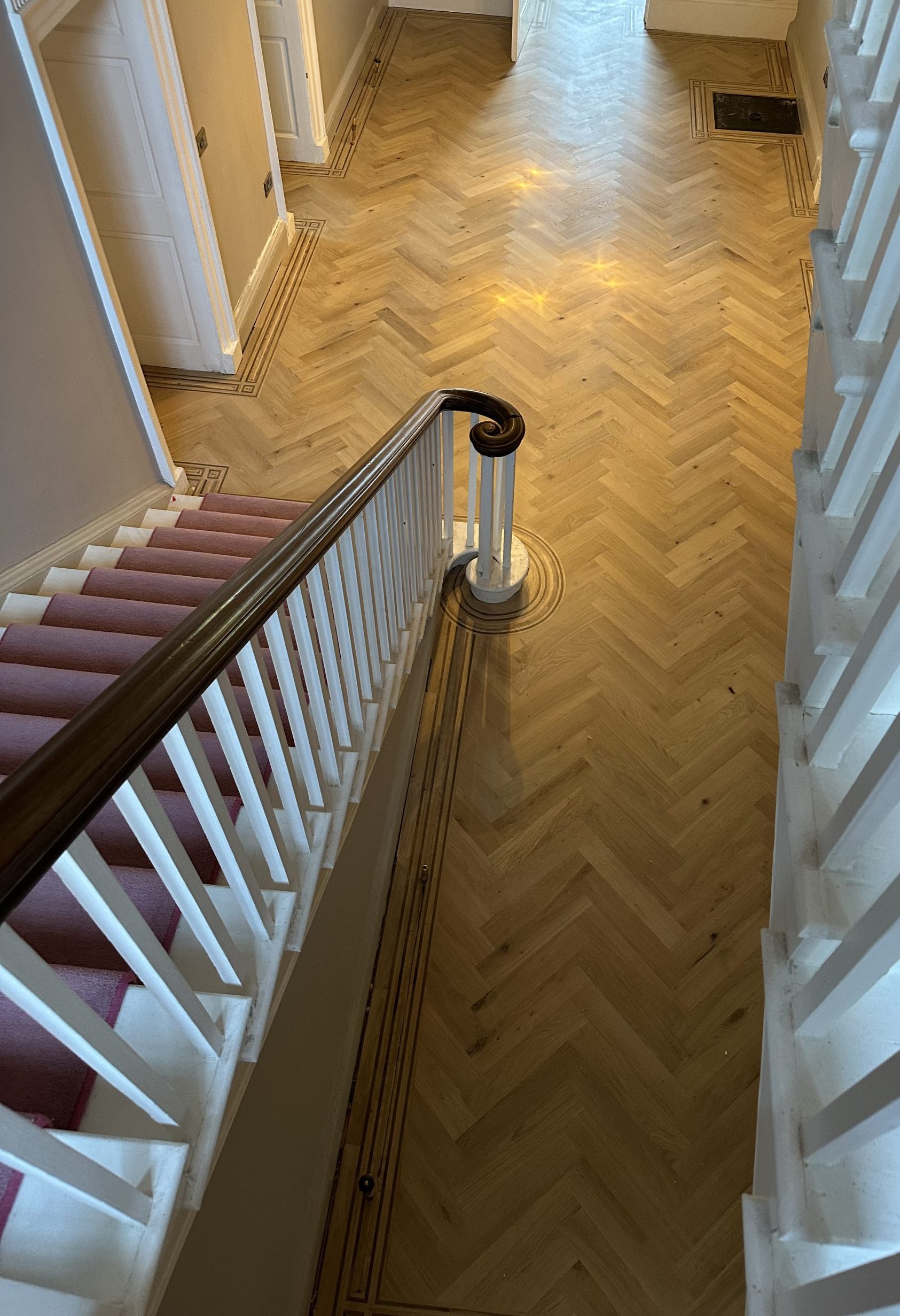 Bespoke oak parquet floor with handmade multi-species border and curved stair detail