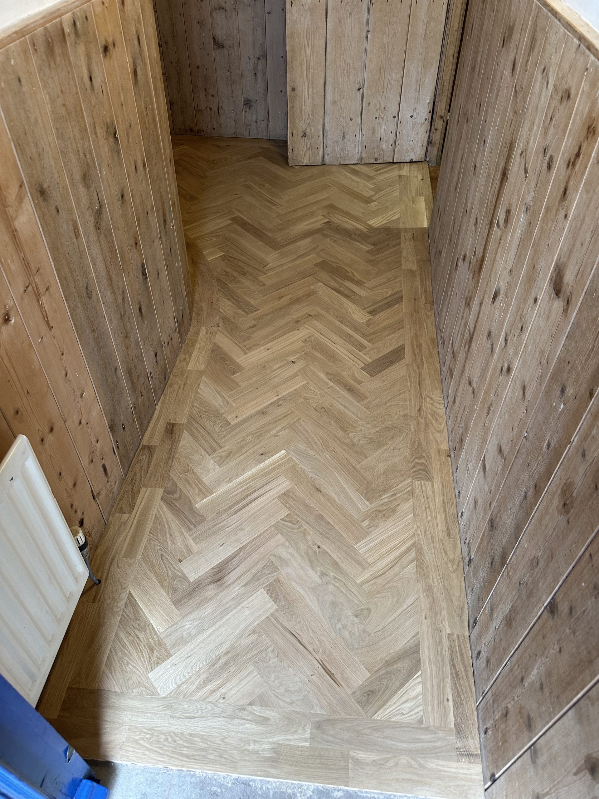 Oak Herringbone Hallway Flooring – Seahouses Oak herringbone flooring with timber border in a wood-panelled hallway in Seahouses