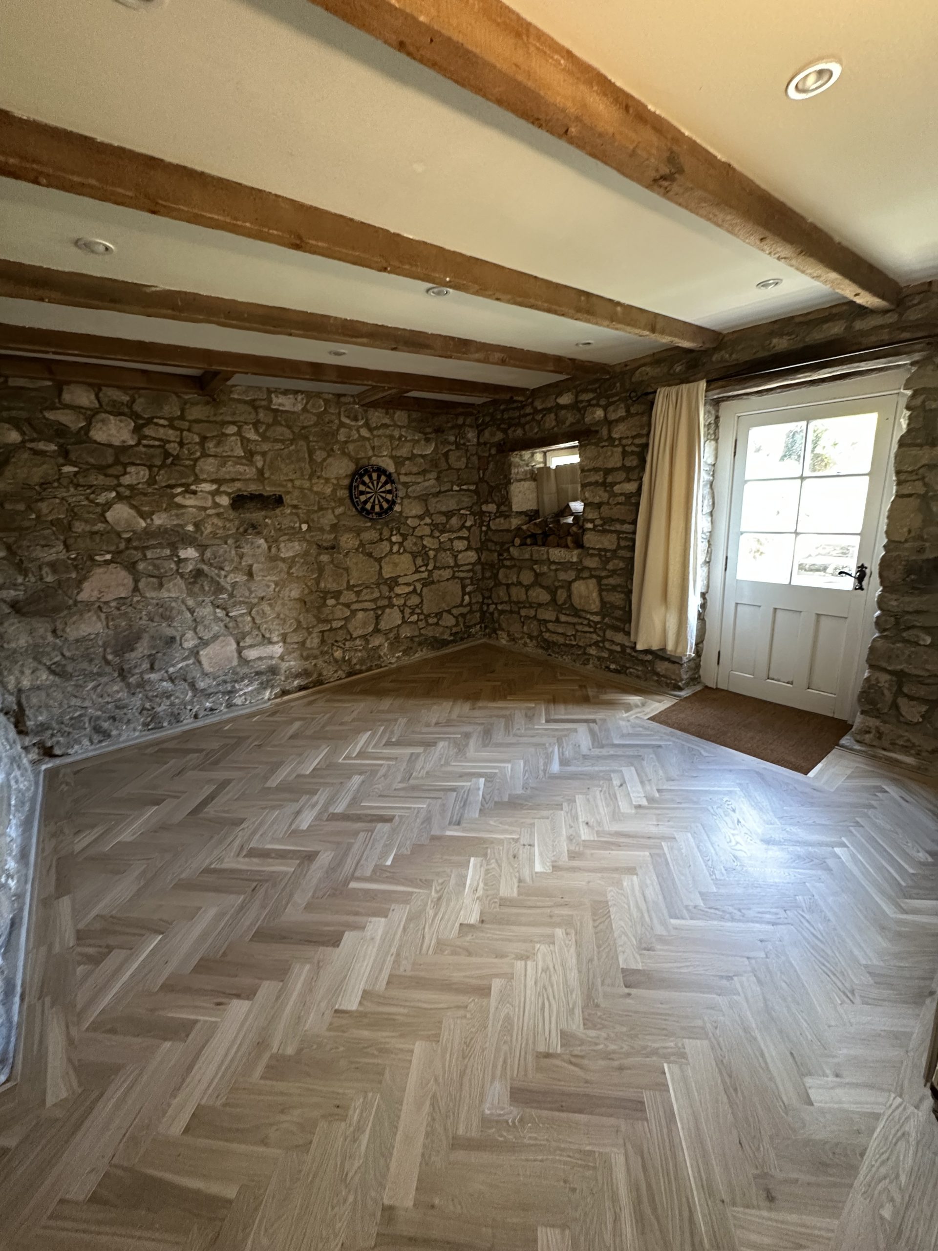 Oak Herringbone Flooring Installation – Seahouses Completed oak herringbone flooring in a stone-walled room in Seahouses, Northumberland