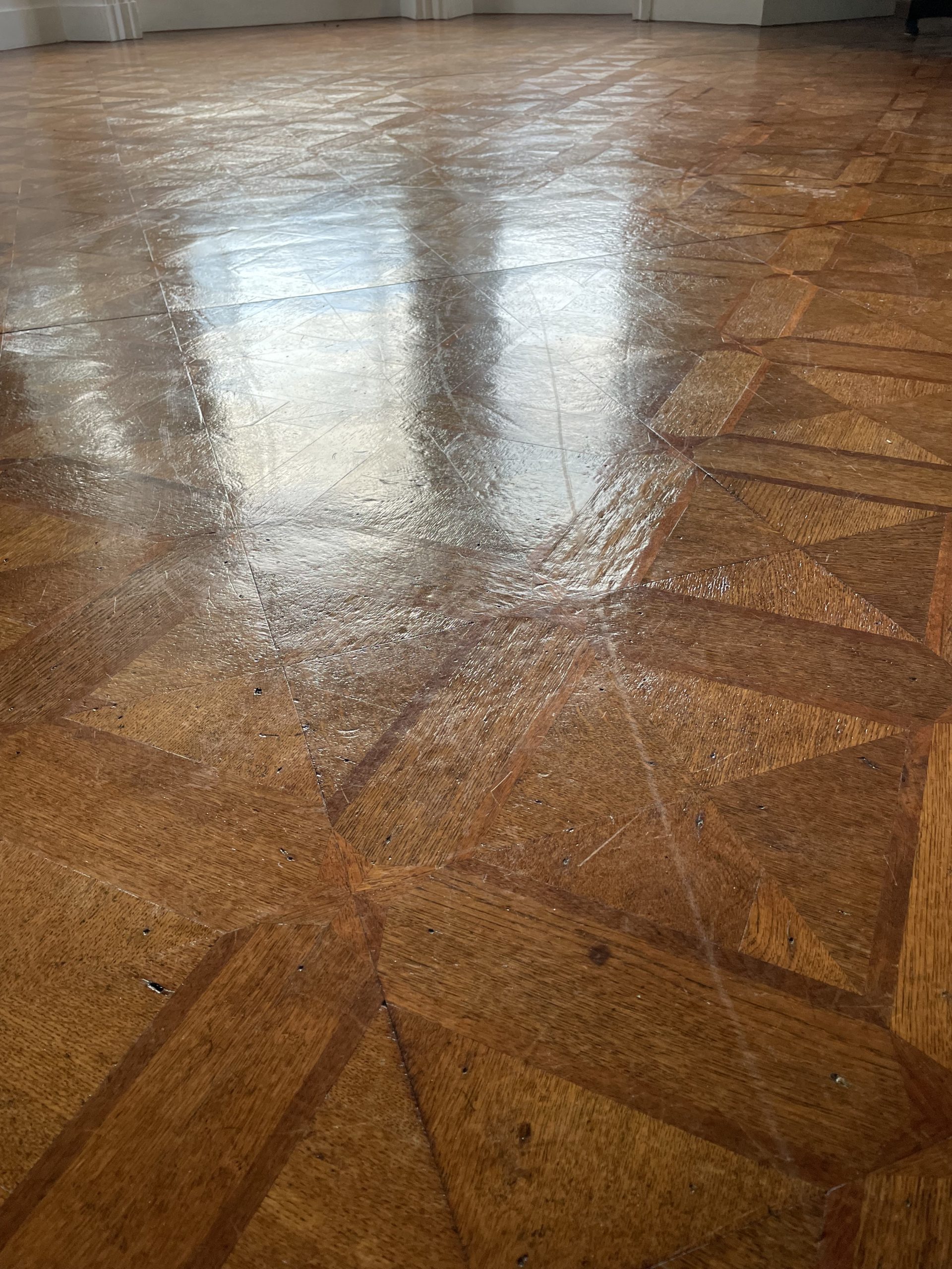 Close-up of worn geometric parquet flooring before sanding and restoration near Berwick-upon-Tweed