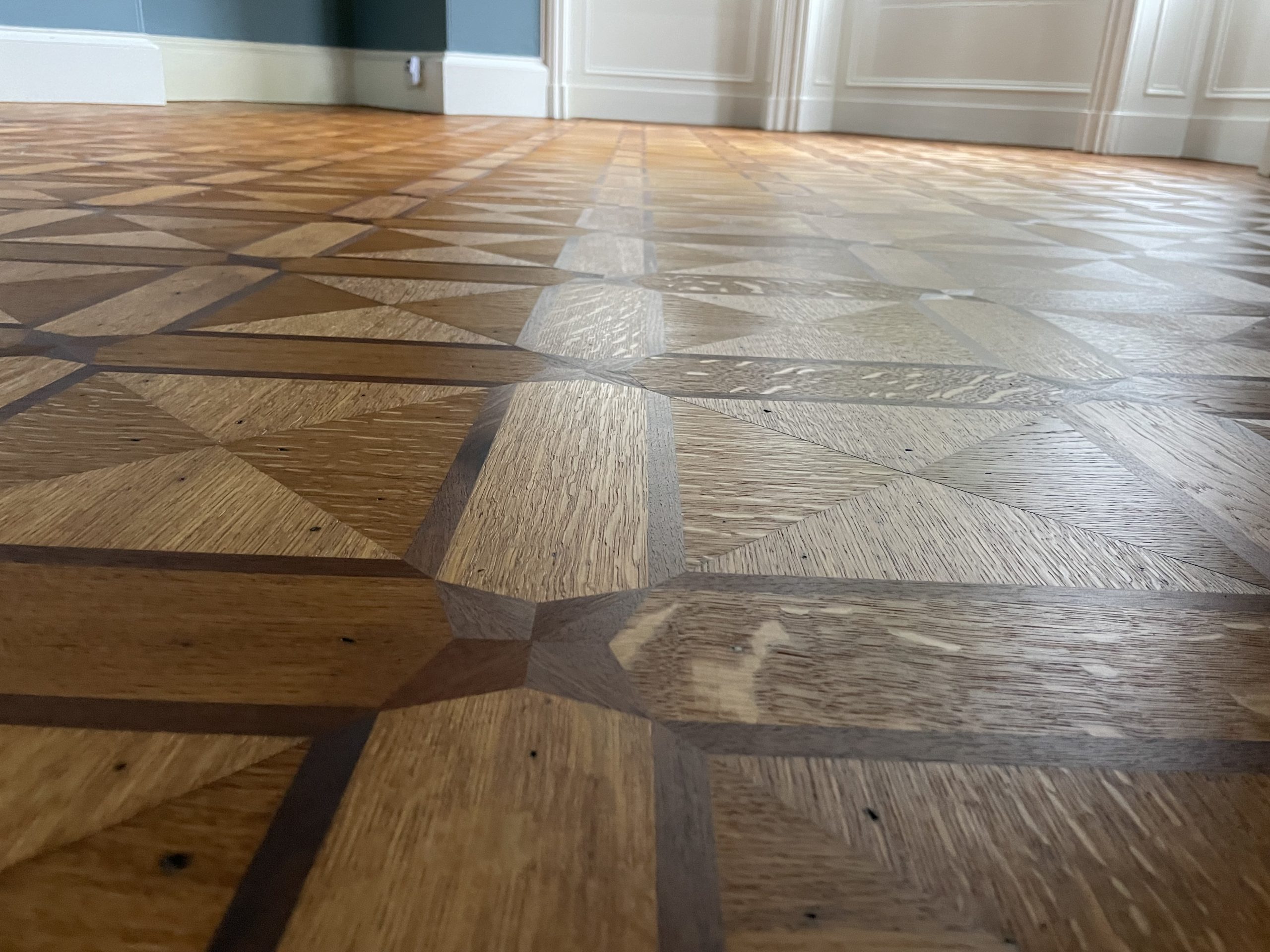 Close-up of restored geometric parquet flooring highlighting the intricate timber design